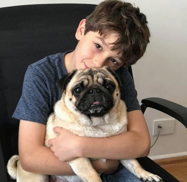 A boy hugs a small dog in a chair.