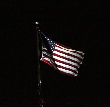 a flag flying at night with lights on it