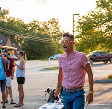 Lawrence wearing sunglasses, walking with his bike