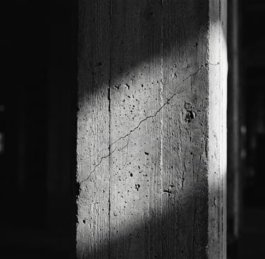 Fotografia editorial em preto e branco de uma viga de concreto sob pressão.