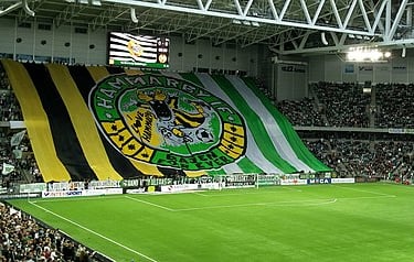 Blick auf die Spielfläche und die vollbesetzten Tribünen der Tele2 Arena, Heimstadion von Hammarby IF, mit Fans, Fahnen und F
