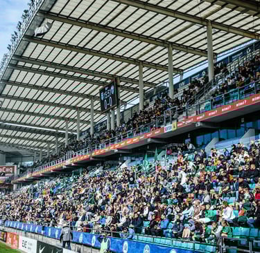 Fans von FC Flora Tallinn in grün-weißen Farben stehen dicht gedrängt auf der Tribüne und feuern ihr Team mit Fahnen