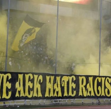 Leidenschaftliche AEK-Athen-Fans in gelb-schwarzen Farben mit Fahnen und Pyrotechnik auf den Rängen des Agia-Sofia-Stadions.