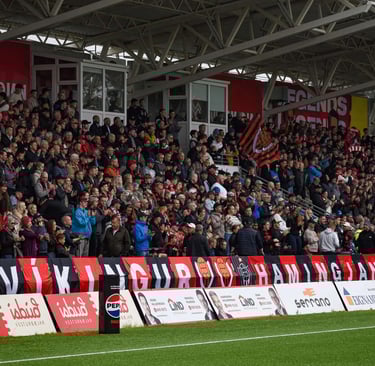 Luftaufnahme des Víkingsvöllur-Stadions in Reykjavík mit Spielfeld, Tribünen und umliegender Landschaft.