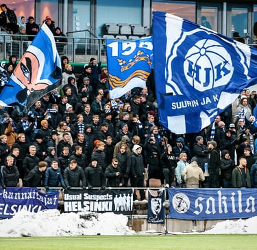 Fans von HJK Helsinki feiern in der Bolt Arena, mit blau-weißen Schals, Tribünen im Hintergrund und lebendiger Stadionstimmun