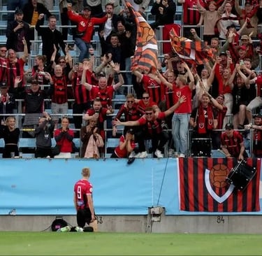 Luftaufnahme des Víkingsvöllur-Stadions in Reykjavík mit Spielfeld, Tribünen und umliegender Landschaft.