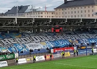 Fans von HJK Helsinki feiern in der Bolt Arena, mit blau-weißen Schals, Tribünen im Hintergrund und lebendiger Stadionstimmun