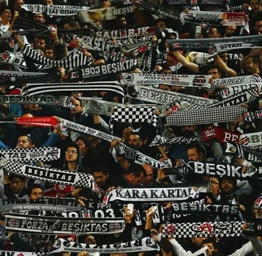 Beşiktaş-Fans in schwarz-weißen Farben jubeln und schwenken Fahnen im Stadion.