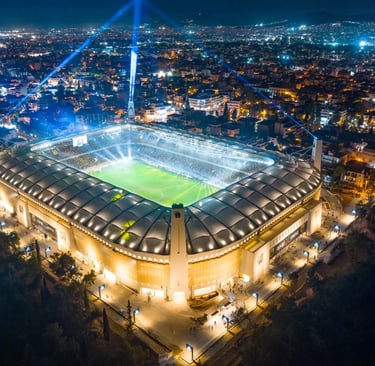 Luftaufnahme der OPAP Arena in Athen, Heimstadion von AEK Athen, mit vollem Spielfeld, Tribünen und umgebender Stadtkulisse