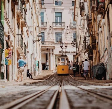 Historische gelbe Straßenbahn in Lissabon fährt durch eine enge Altstadtgasse