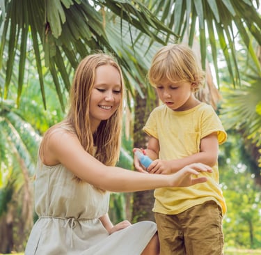 Mom helping child apply mosquito repellent in tropical outdoor setting