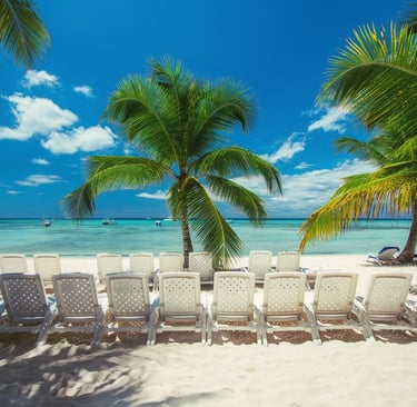 Beach chairs under palm trees on Saona Island with white sand and turquoise Caribbean water