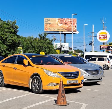 Taxi service in Dominican Republic with yellow car parked near restaurants and shops