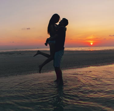 a man and woman kissing on the beach during a sunset on their honeymoon in the dominican republic