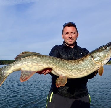 Ein Mann ist auf einem Boot und hat in Schweden einen großen Hecht gefangen.
