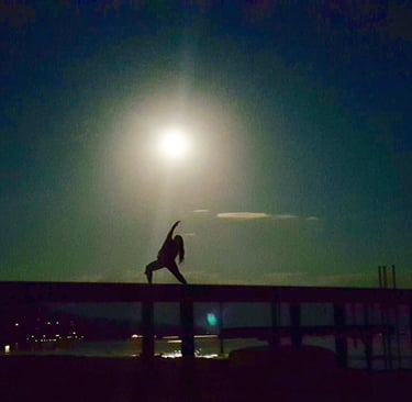 Kiera Goetz under a full moon at Lake Tahoe while the water is low in reverse warroir yoga pose