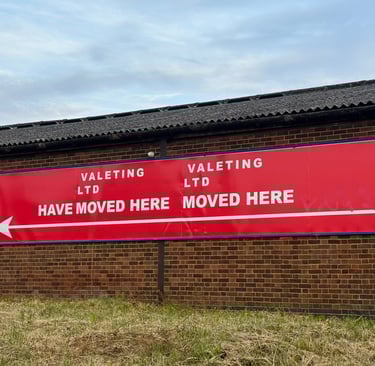 Big red sign on brick wall that reads Valeting Ltd have moved here Valeting Ltd moved here