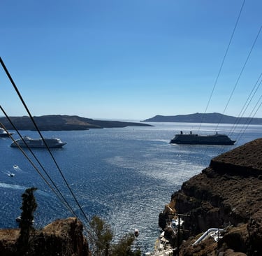 Cruise ships near a cliff off the shore of a Greek island.
