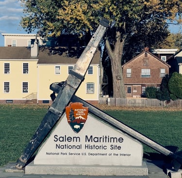 a large metal anchor on a grassy field with a sign saying salem maritime national historic site