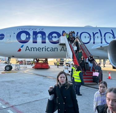 A silver Boeing 777 on the tarmac with a set of stairs pulled next to it