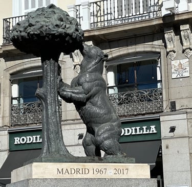 A statue of a bear leaning against a madroño tree