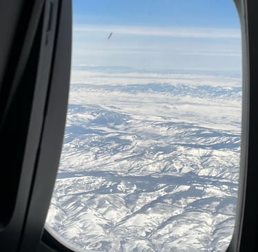 a view of a plane window looking out over a snowy landscape