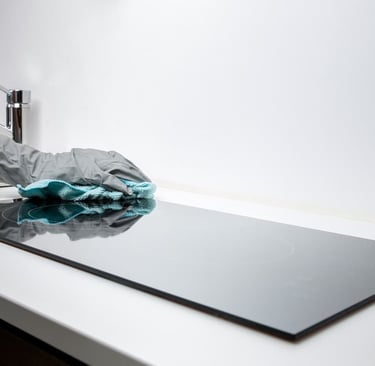 Une personne nettoyant la table de cuisson avec un chiffon posé dessus.