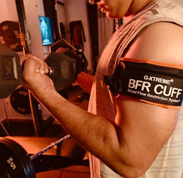 "Client performing upper limb blood flow restriction training with pneumatic cuff on biceps