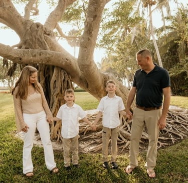 a family of four standing in front of a tree