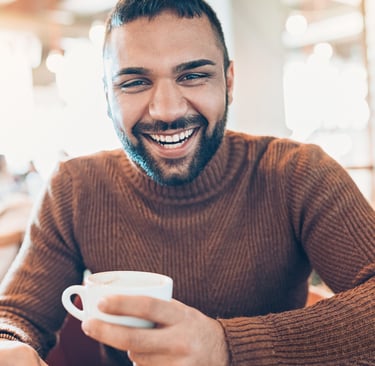 a man with a beard and a cup of coffee, feeling less stress and burnout due to stress therapy