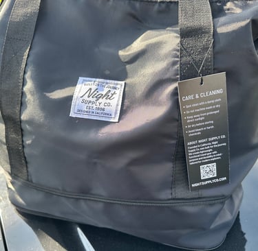 Black Night Supply Co. duffel bag with logo patch and visible care tag details