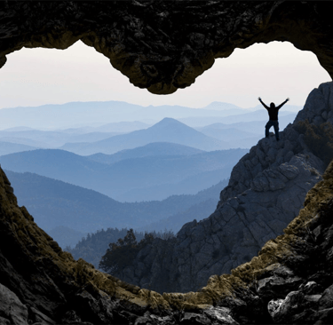 a person standing on a mountain top with a heart shaped hole in the middle of