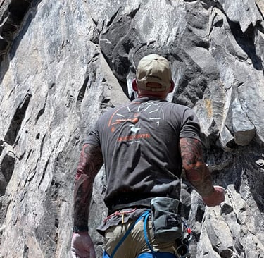 Carl Gregory is climbing a rock face on a mountain