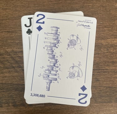 The Two of Diamonds is shown face up, with a patent drawing of a balanced crankshaft from an engine