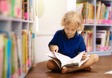 young boy in a library reading a book