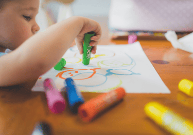 preschooler drawing with markers on paper