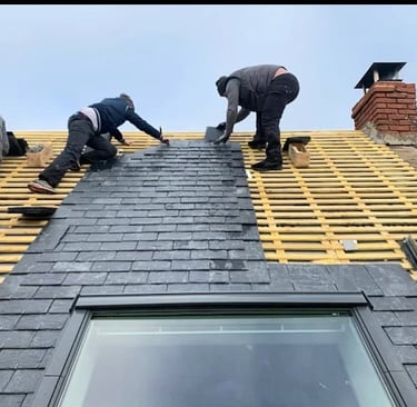 Trois couvreurs posant des ardoises sur charpente de toiture avec Velux