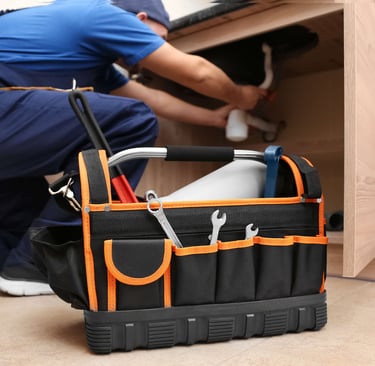 Professional plumber with tool box repairing leaking kitchen sink drain.