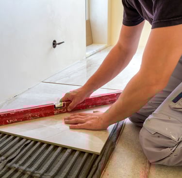 Tiler on the floor installing porcelain tiles and leveling.