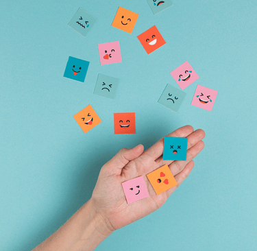 image d'une main tenant des papiers avec des visages d'émotions