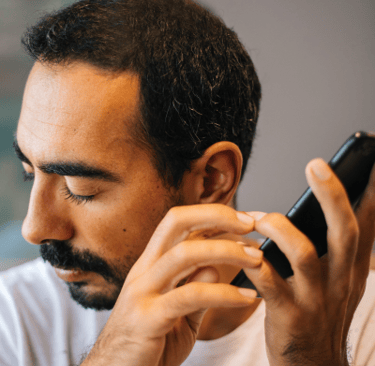 Man with refractive error using adaptive technology screen reading software on cell phone accessible