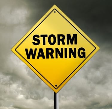 A yellow sign saying Storm Warning with stormy clouds in the background