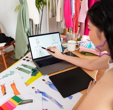 girl-making-illustration-on-laptop-with-sketches-lying-on-table