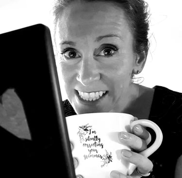 Author-editor K.A. Hough smiles as she holds a mug which reads, I'm silently correcting your grammar