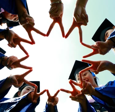 Group of graduates in blue gowns and caps forming a star shape with their fingers while celebrating