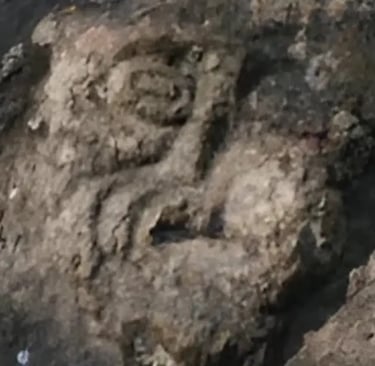 Eerie stone carving known as the Devil’s Face (Mostasù or Diaol) covered in moss along the Sentiero 