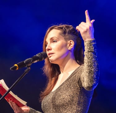 Britta Kah auf der Bühne. Poetry Slammerin mit rotem Buch