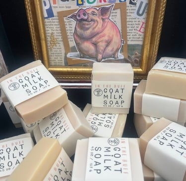 A stack of In the lard soap bars in front of a framed pig illustration.