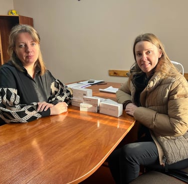 дві жінки сидять за столом з упаковками ліків