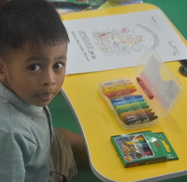 A photographer takes a picture of a boy drawing at a folding table